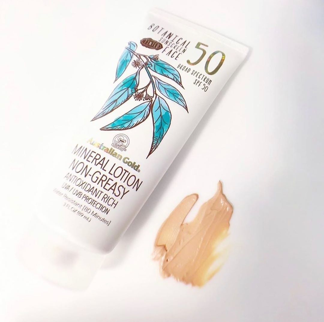 A flatlay of a tube of sunscreen next to a smear of the product