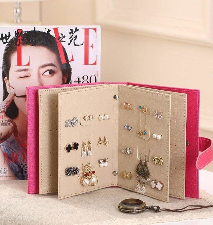 An open earring storage book holding several pairs of earrings next to a magazine