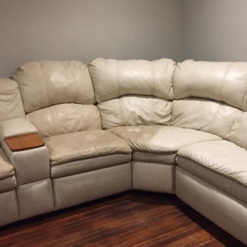 A reviewer showing white leather chairs that look darker and slightly brown on one side but brighter and cleaner on the side that was cleaned with the product