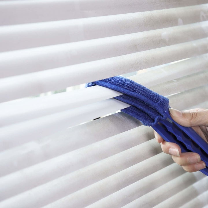 Model swiping three-pronged cleaner across blinds