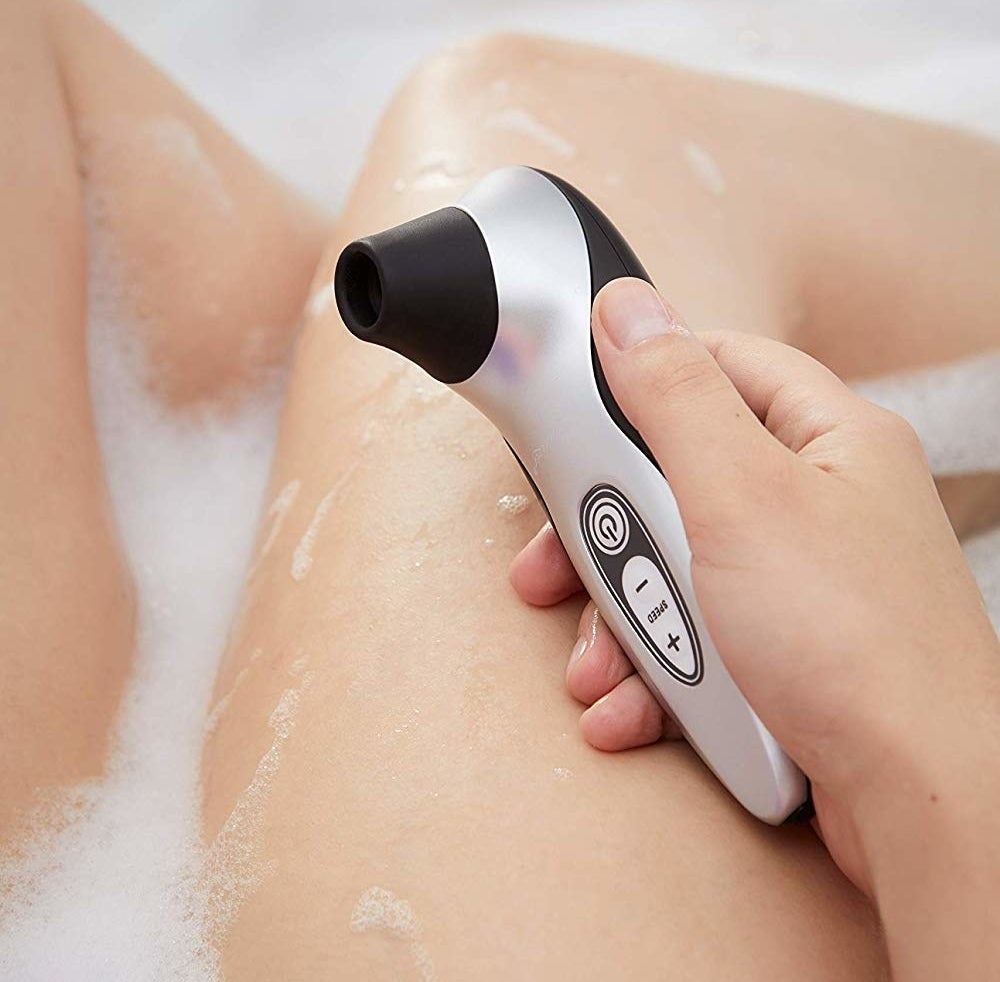 A person holding the vibrator against their leg in the bath