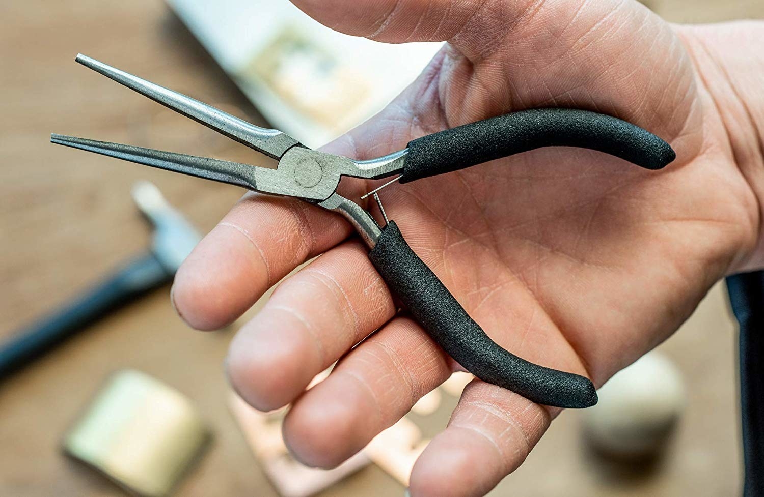 hand holding the pair of needle nose pliers