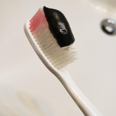 a reviewer photo of the black charcoal toothpaste on their toothbrush
