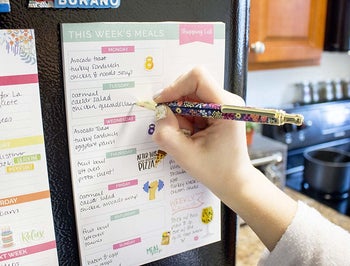 a hand filling in the sheet while it's on the refrigerator