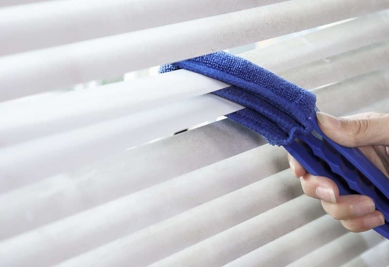 a person using the microfiber tool to clean blinds