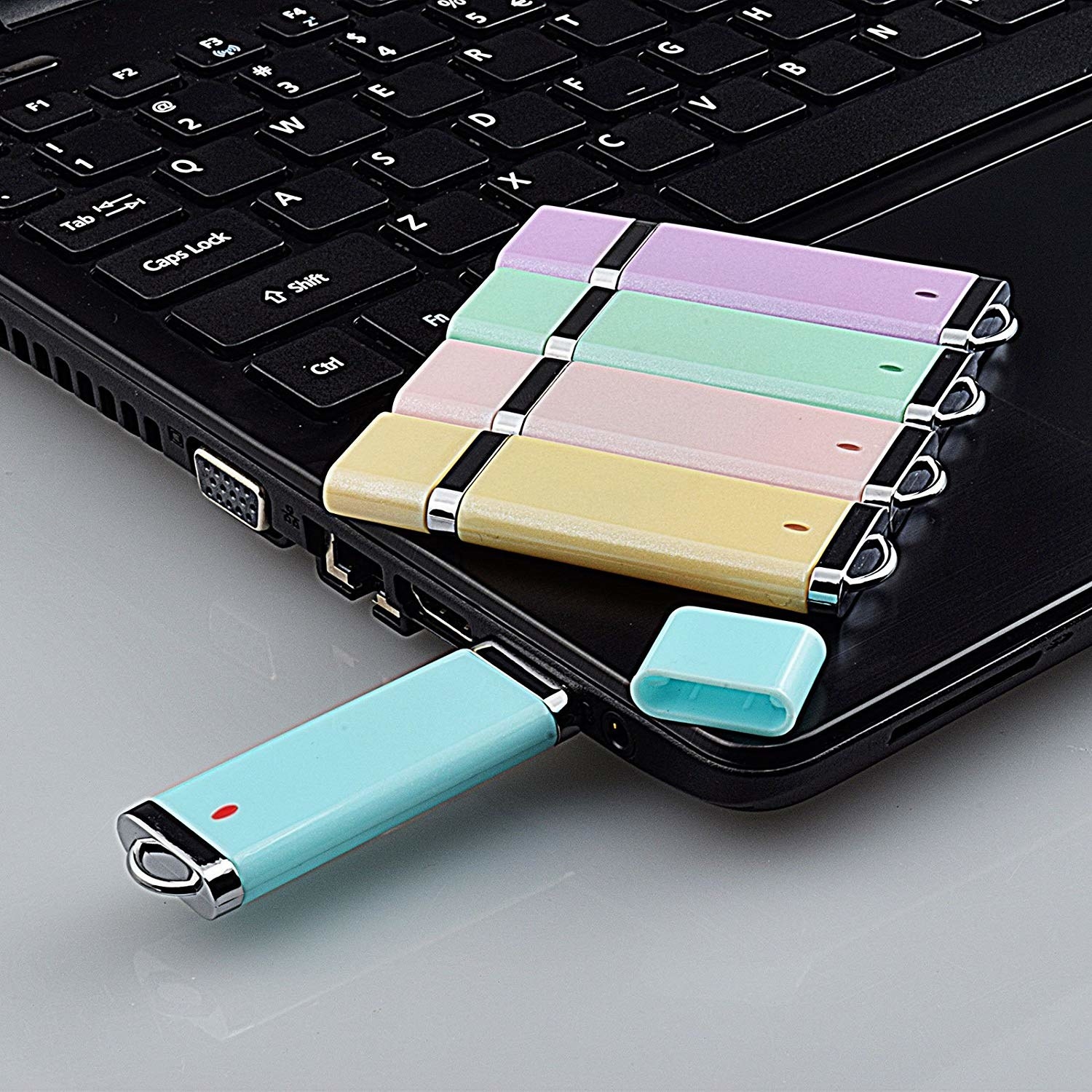 Four USB flash drives sitting on top of a laptop One USB flash drive inserted on the side of the laptop