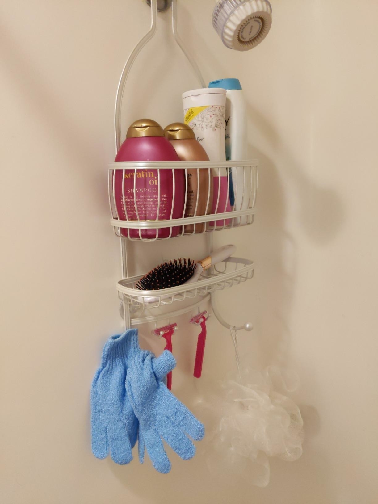 reviewer&#x27;s white over-shower head rack holding their toiletries 