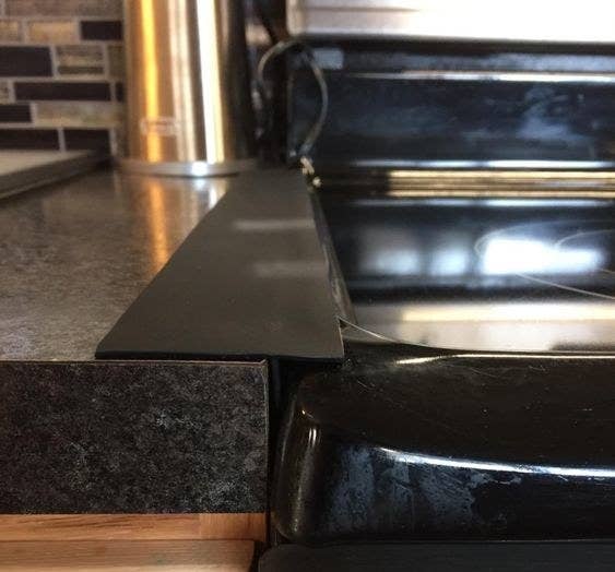 Reviewer&#x27;s picture of the gap cover placed between their stove and counter 