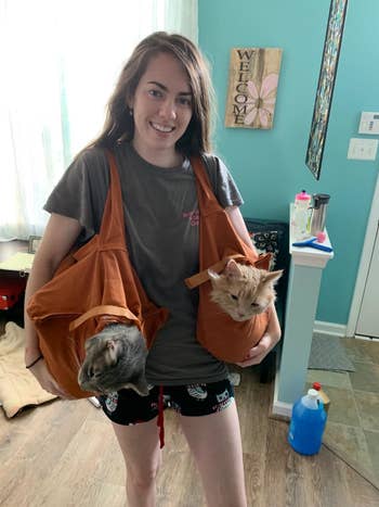 Reviewer with two bags on their shoulder and one cat in each bag