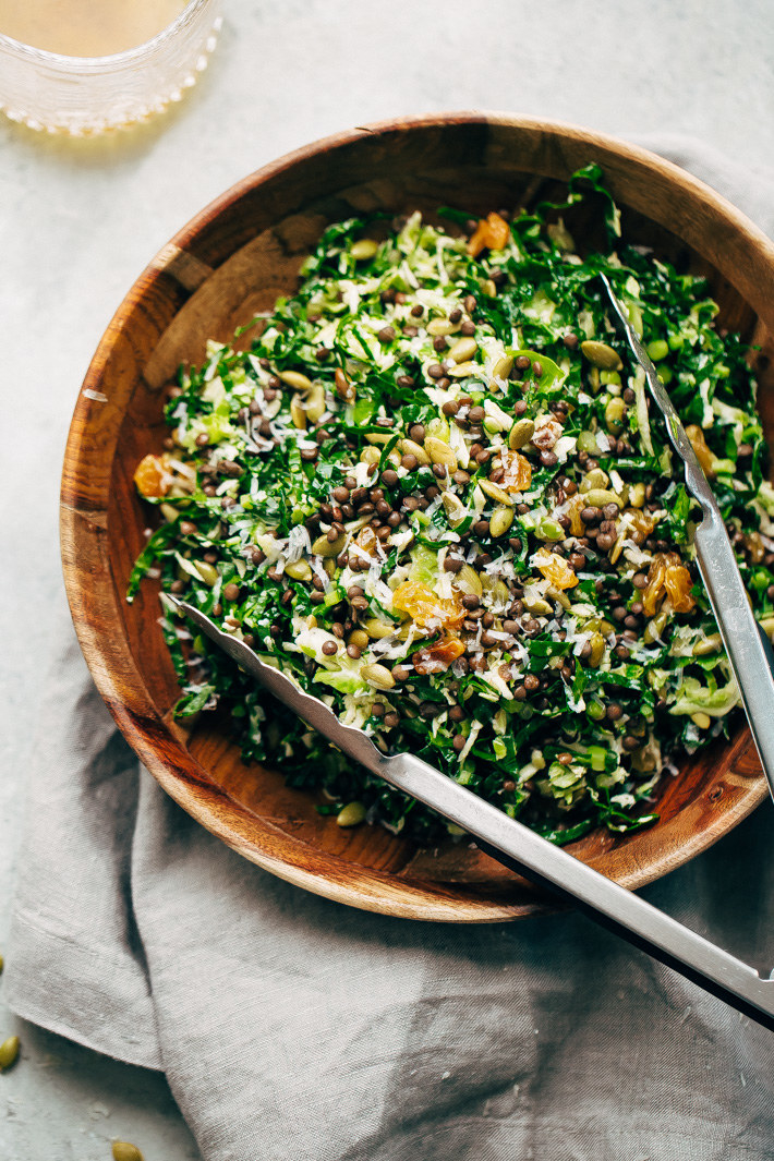 A salad topped with lentils, nuts, and cheese in a bowl