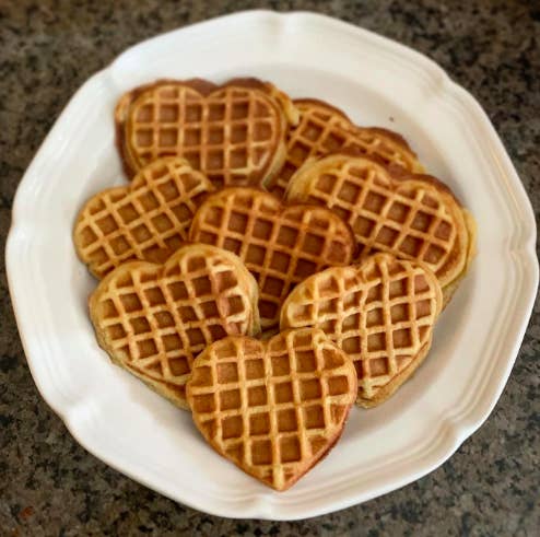 A white plate holding heart-shaped waffles that are the width of a fist.