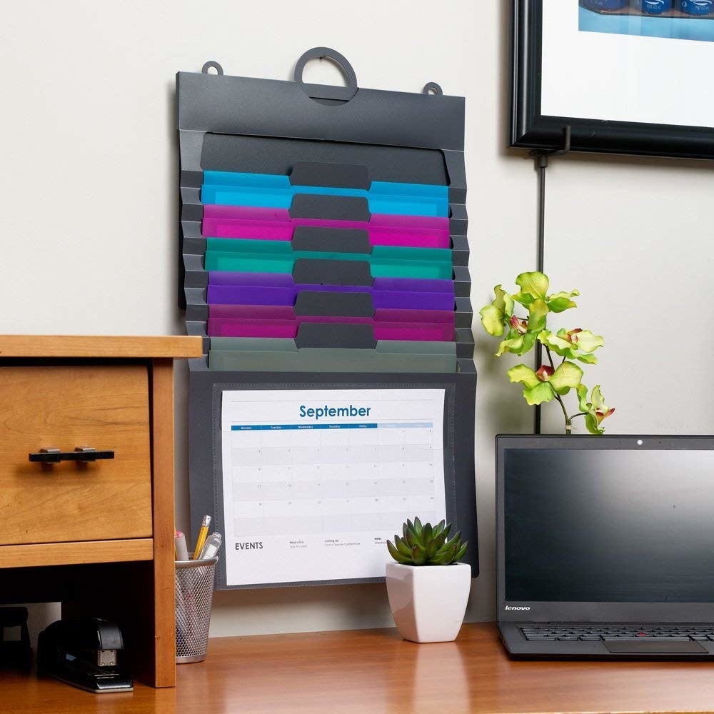 The file cascaded to hang on a home office wall; there&#x27;s a loop for the nail, six file folders, and a clear slot for something like a calendar print-out in the front