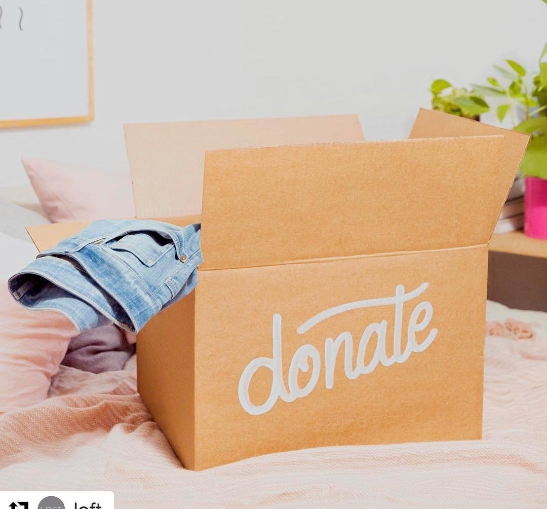 A box with the word &quot;donate&quot; written on it, a pair of jeans sticking out of the top