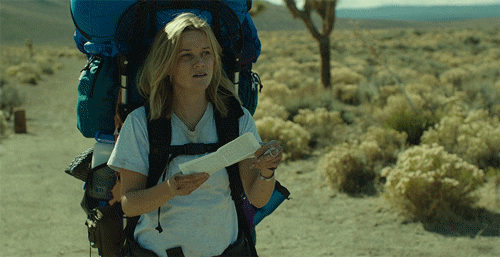 A gif from the movie Wild of Reese Witherspoon holding a map in the desert with a large backpacking pack on.