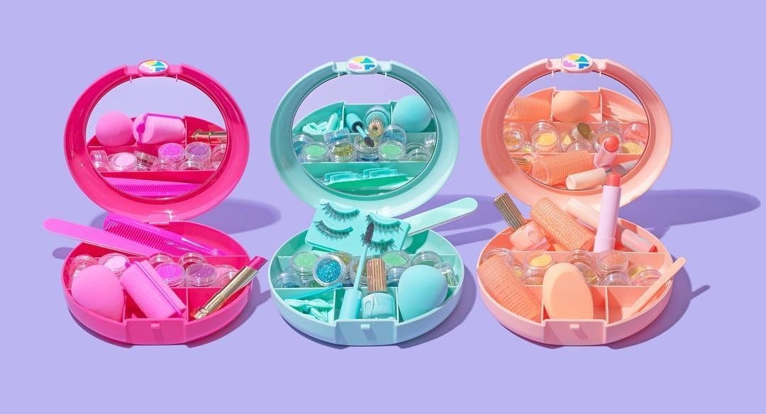 Three small round plastic makeup cases next to each other Each has a mirror on the inside and is filled with beauty products and tools