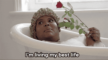Gif of a woman in a bath holding a rose saying &quot;I&#x27;m living my best life&quot; 