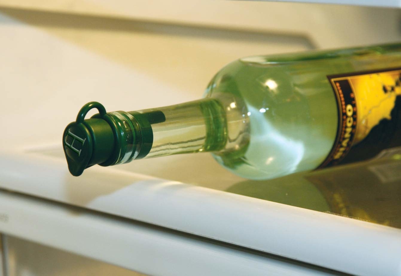 The wine corker plugged into a bottle of liquor laying on its side in the fridge