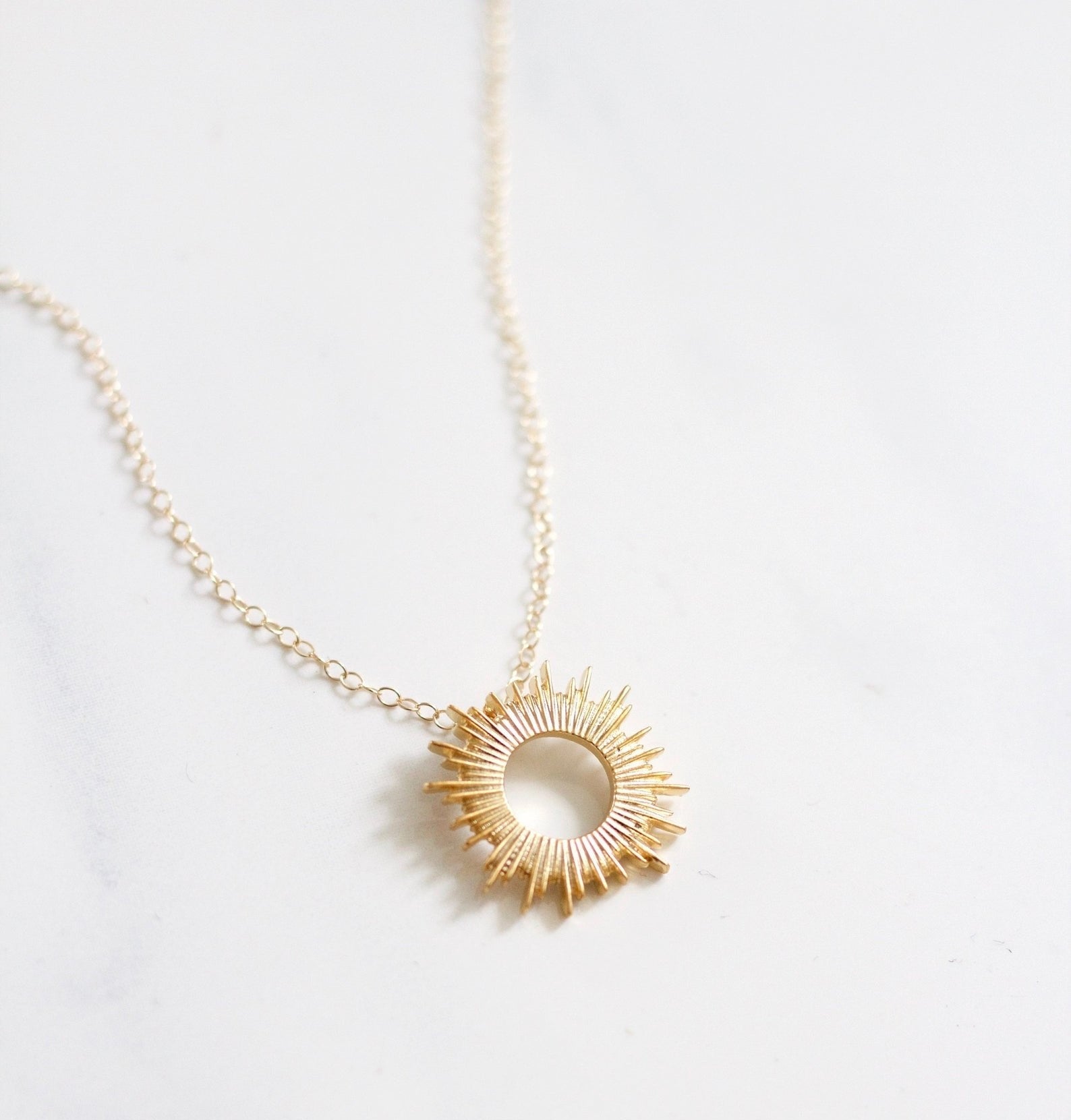 the gold sunburst necklace on a chain