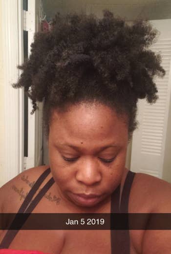 A reviewer with their kinky natural hair pulled up into a pineapple-style puff