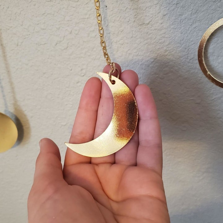 a close-up of a reviewer's crescent moon on a chain attached to the garland