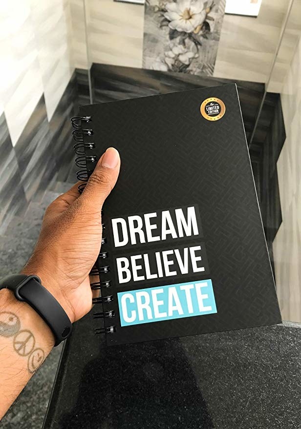 Black spiral bound notebook with the words ‘Dream, Believe, Create’ written on it.