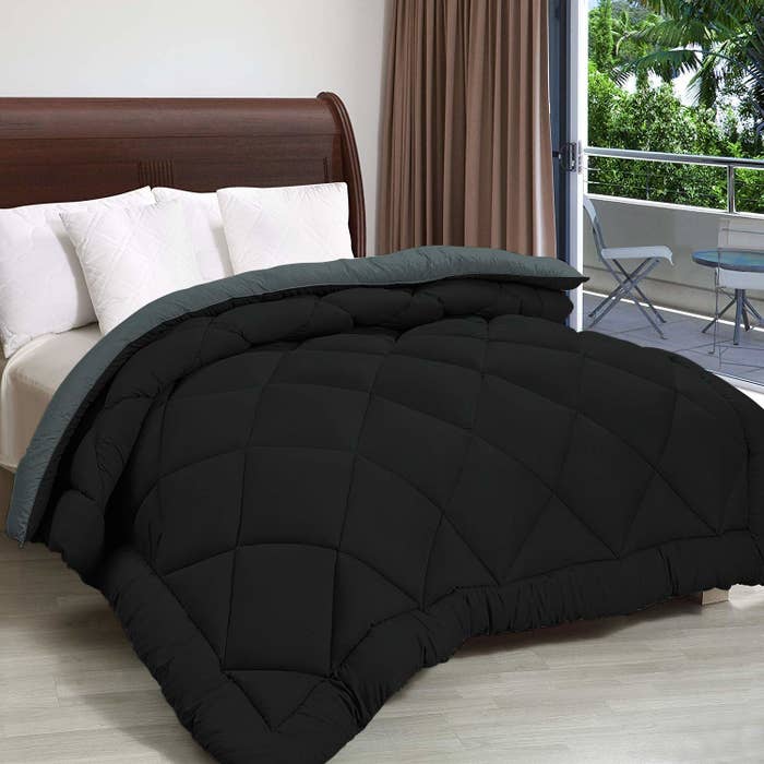 A black comforter spread out over a double bed 