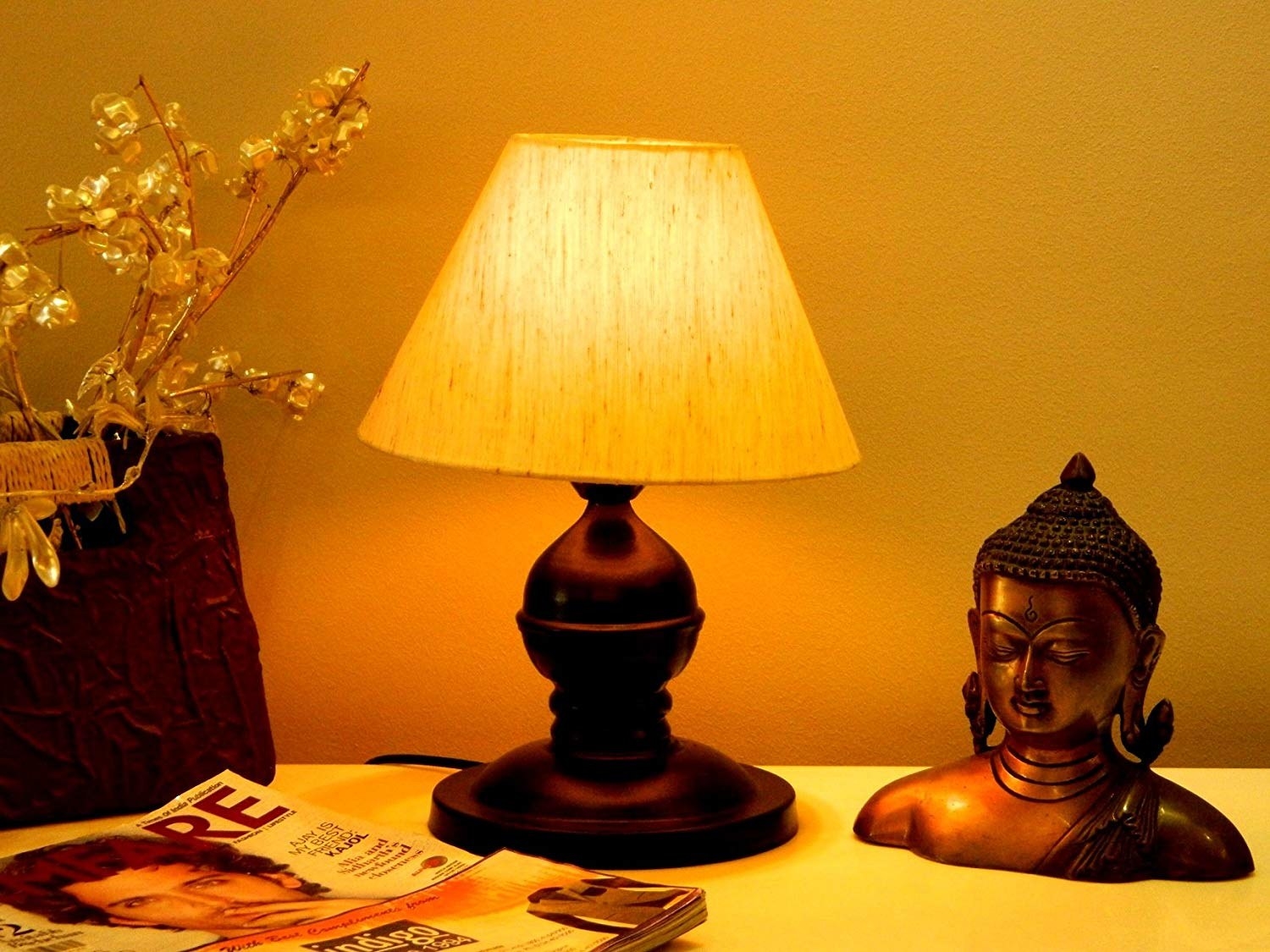 A conical lamp on a table beside magazines