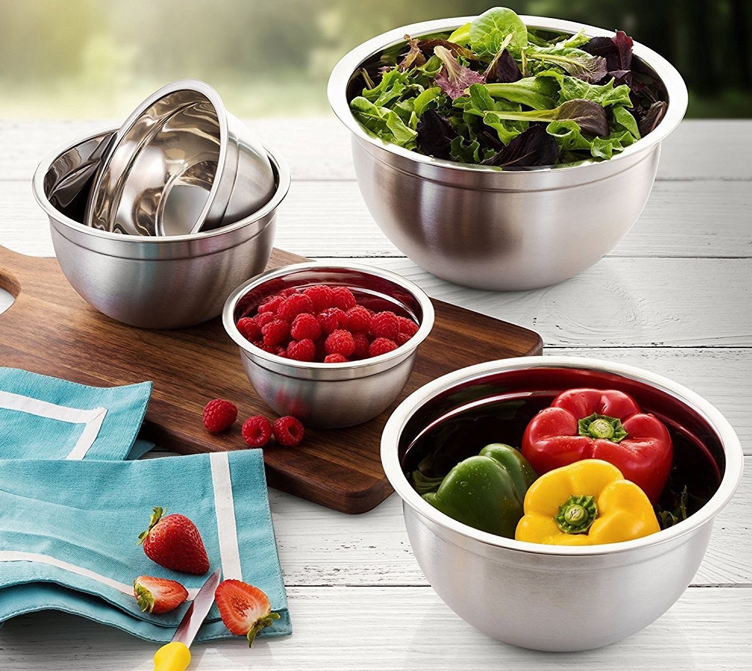 A set of stainless steel bowls filled with fresh fruits and veggies