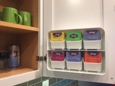 reviewer pic of the tea organizer mounted on the inside of a kitchen cabinet 