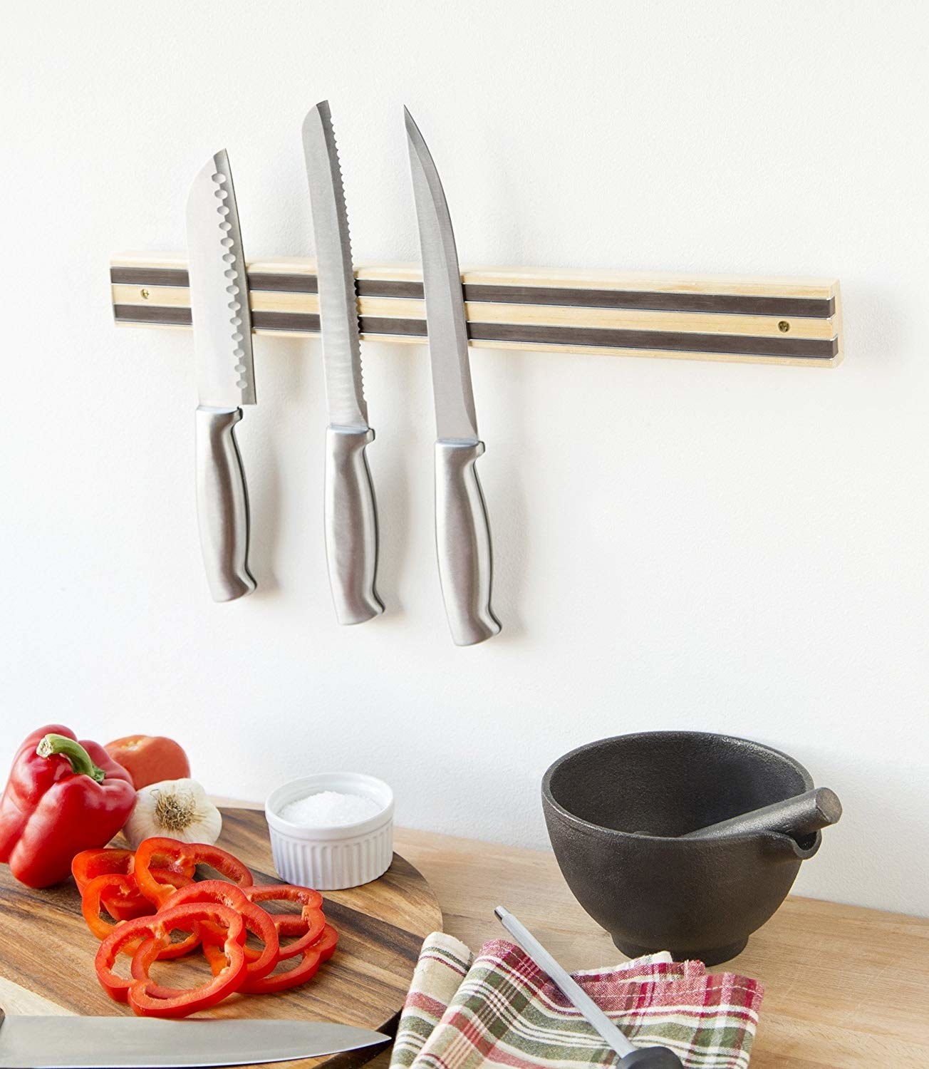 A knife wall strip holding three sharp kitchen knives