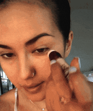 a gif of a buzzfeed editor applying the concealer under her eyes