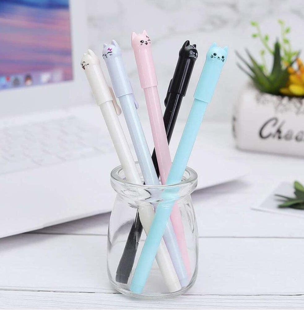 A small glass jar with five pens inside it The pens have little cat faces on the lids