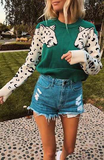 model wears green crewneck with leopard heads on each shoulder that turn into leopard print sleeves