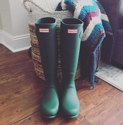 Green knee-high Hunter rain boots inside house 