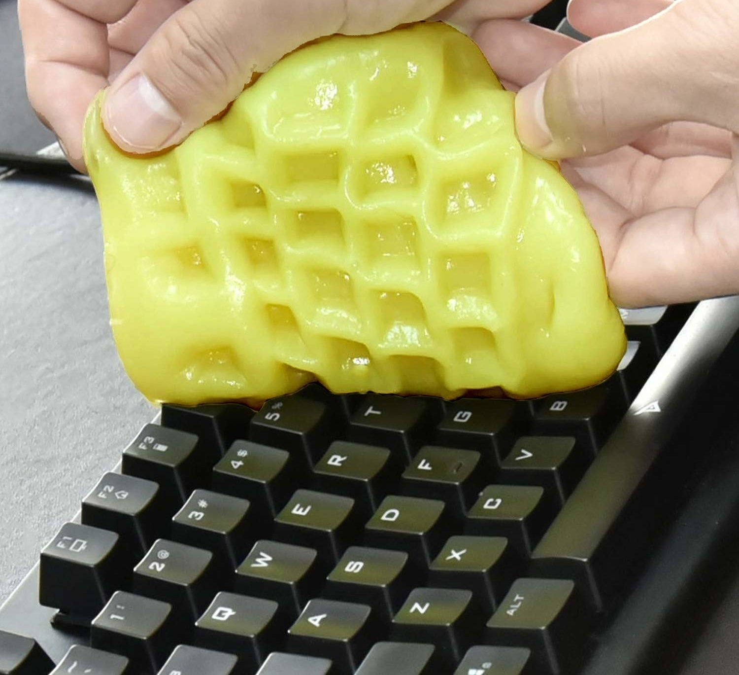 A person using gel cleaning putty to clean a computer keyboard
