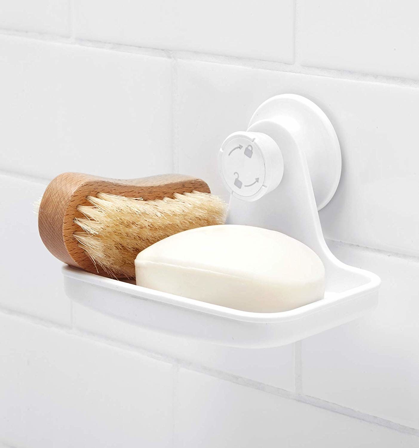 A soap dish attached to a wall in the bathroom with soap and a brush on it