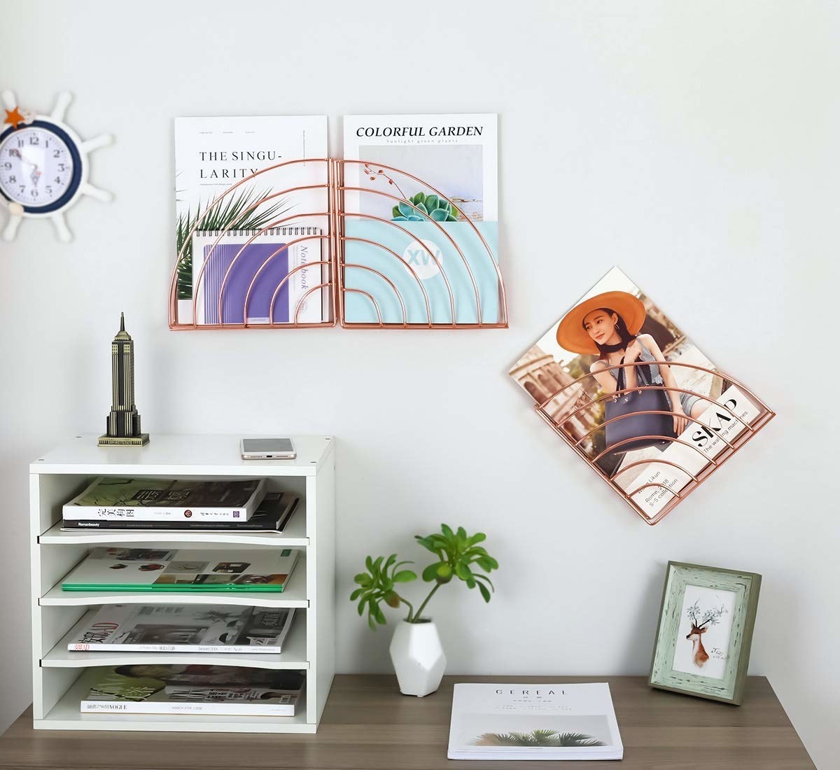 three rose gold pocket shelves on a wall with magazines and notebooks in them