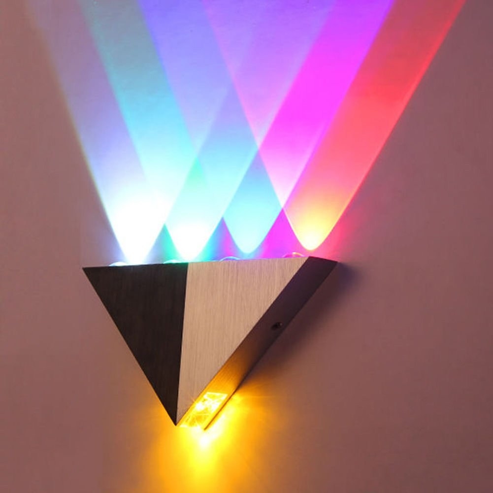 A black and white scone installed on a wall with different coloured lights being projected from it
