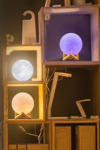 three of the lamps illuminated different colors sitting on a shelving unit 