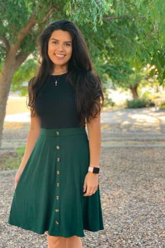 A reviewer wearing the short sleeve dress with a bodice that looks like a black T-shirt and a button-front green skirt