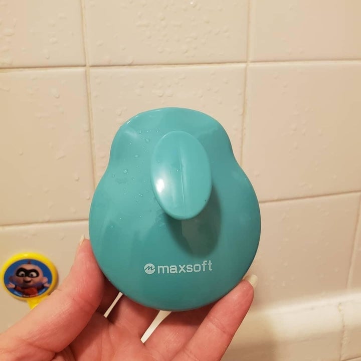 Reviewer holding up the back of blue silicone massager to show finger handle 