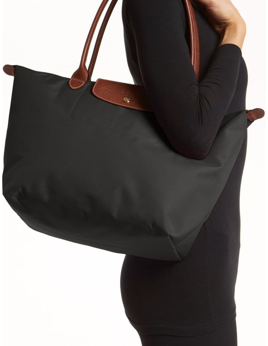 model holding black tote bag with brown leather straps