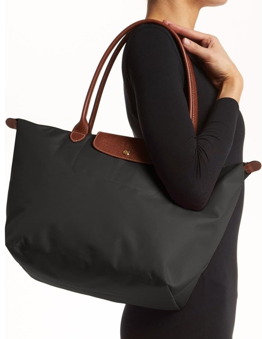model holding black tote bag with brown leather straps