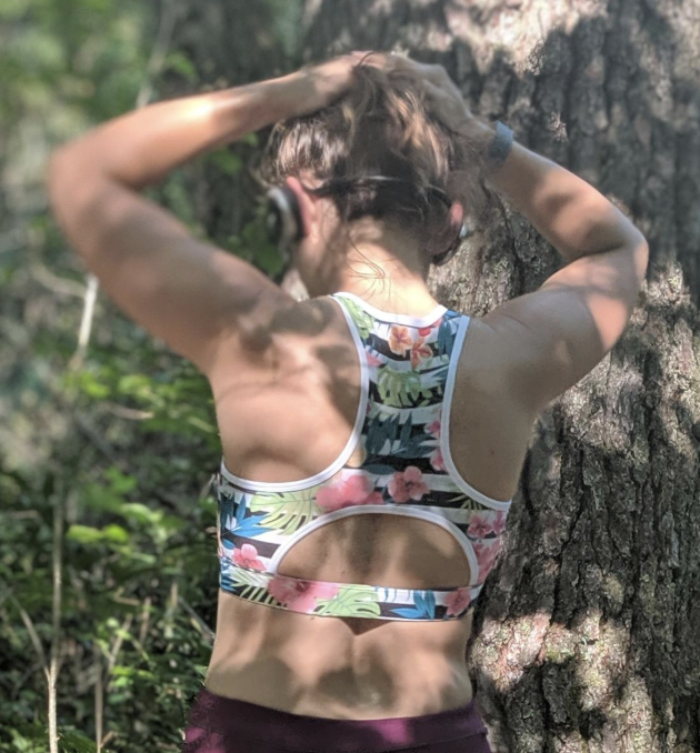 Reviewer shows discreet tech pocket in the back of their floral-printed sports bra