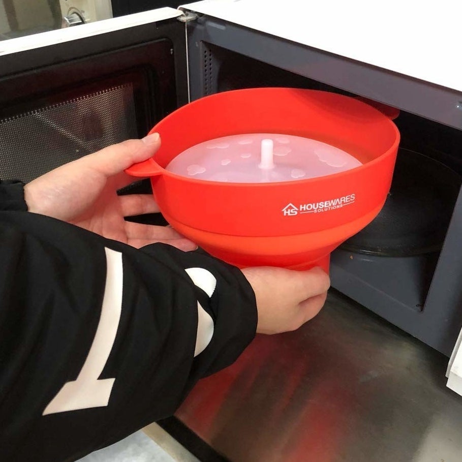 A person putting the popcorn bowl in a microwave