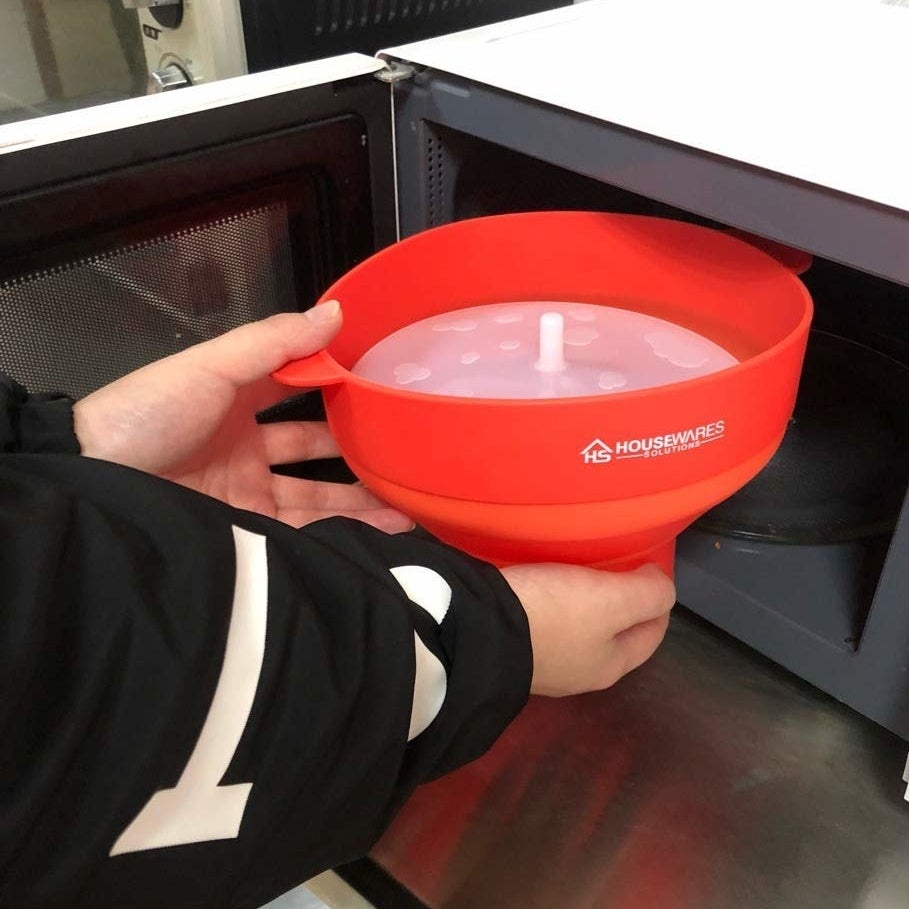 A person putting the popcorn bowl in a microwave