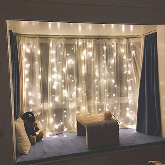 the fairy lights in front of a bedroom window with a curtain