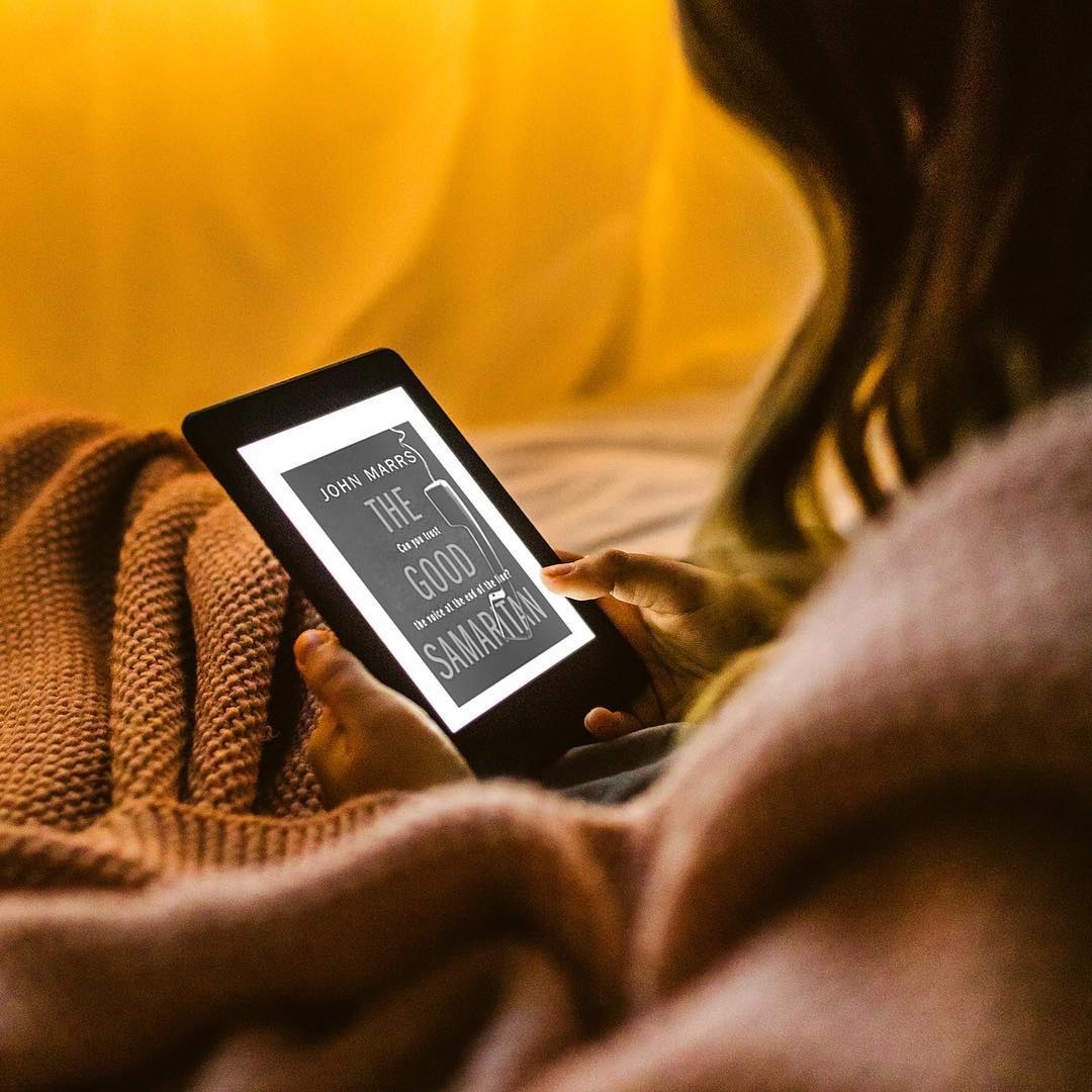 A person reading their Kindle in bed
