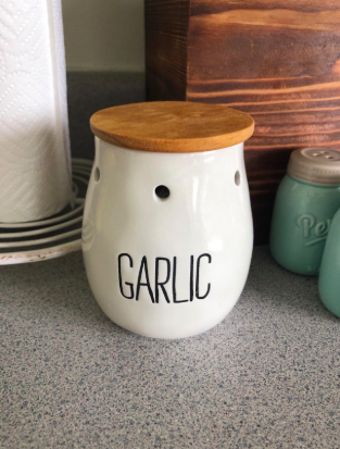 cup-like ceramic container that says &quot;garlic&quot; on it with holes to let the garlic breath and a wood top 