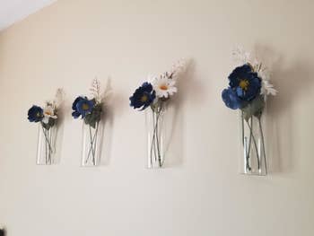 Reviewer photo of four sets of blue and white flowers in cylindrical vases